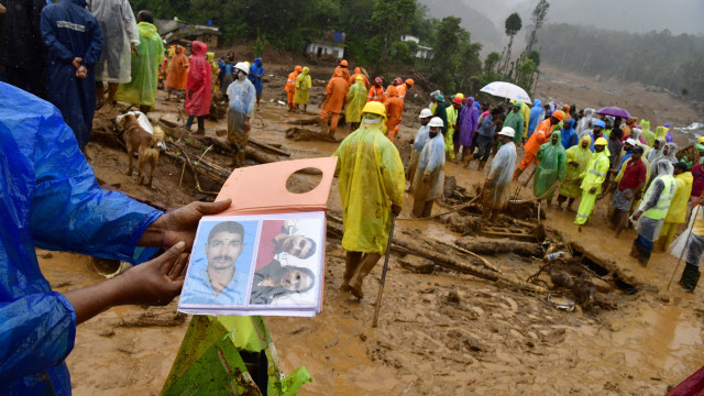 A man holds photos of relative who went missing following landslides in Mundakai, Chooralmala area, Wayanad district, Kerala, southern India, 31 July 2024